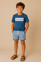 Child wearing a blue t-shirt with 'Jesus Loves Me' text and striped shorts on a beige background