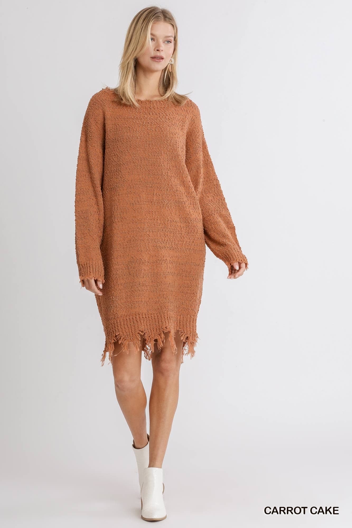 Woman wearing a brown knitted dress with fringe details on a white background