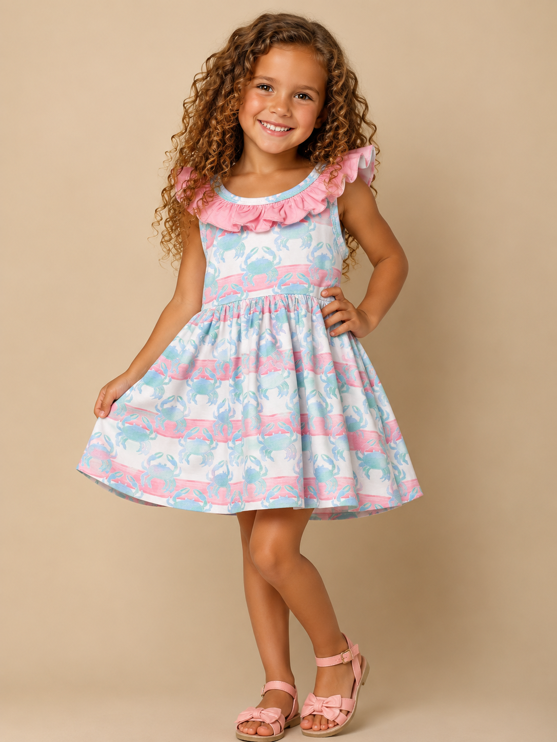 Young girl wearing a colorful dress with ruffled details on a beige background