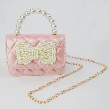 Pink handbag with a bow and pearl handle on a light gray background
