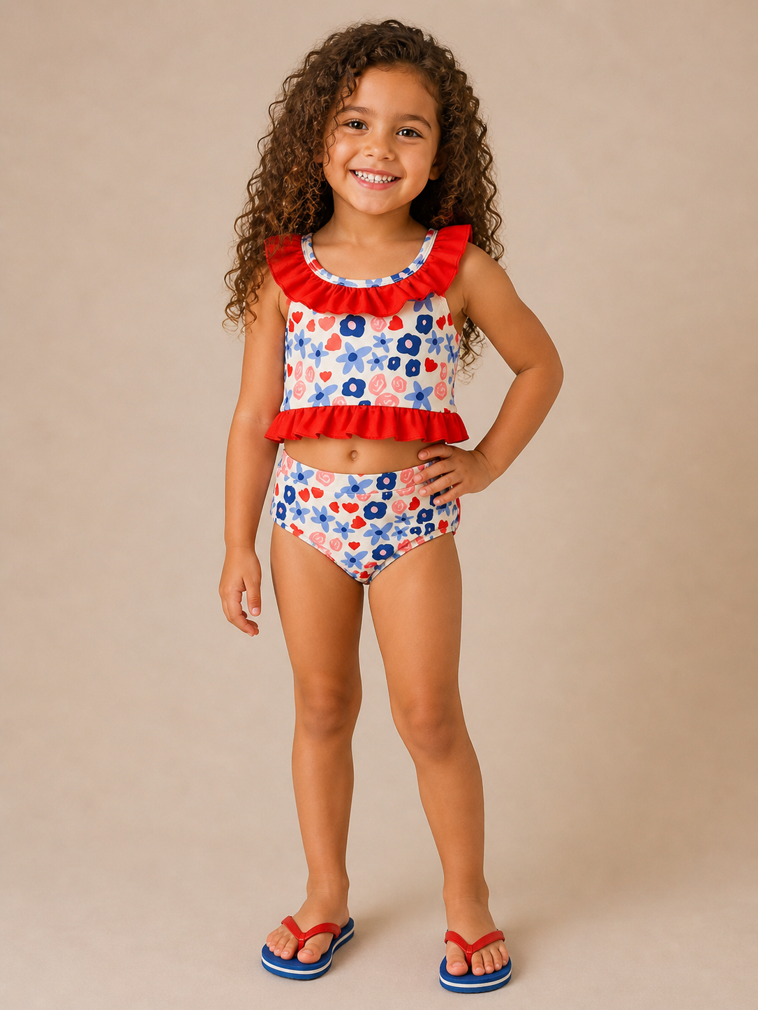 Young girl wearing a red, white, and blue swimsuit with ruffled top on a beige background