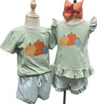 Two children's outfits on mannequins with pumpkins and checkered shorts.