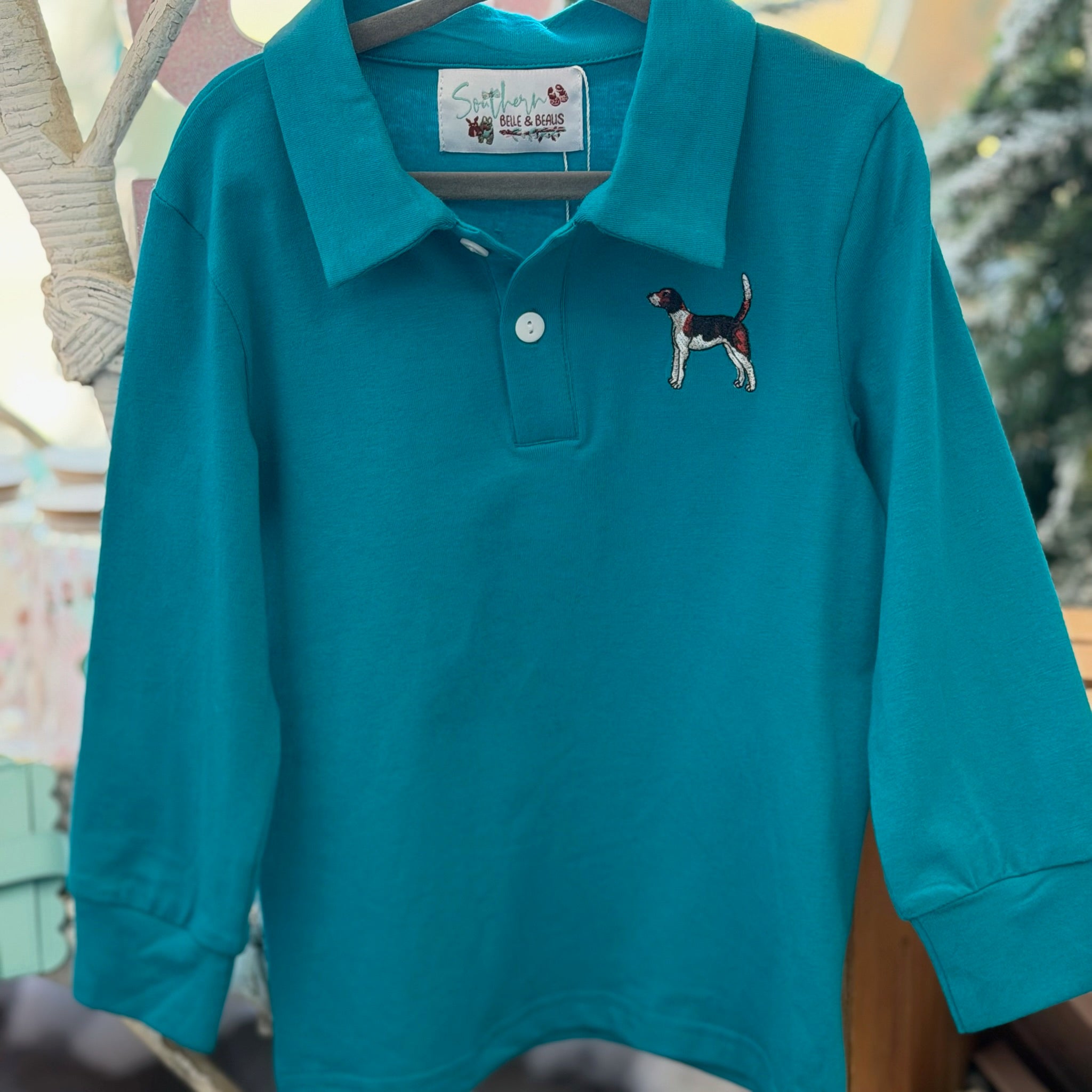 Teal long-sleeve polo shirt with dog embroidery on a hanger