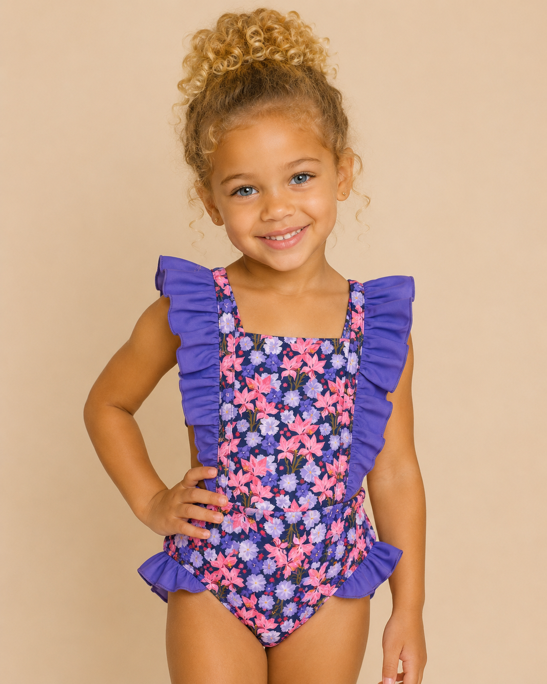 Child wearing a floral swimsuit with purple ruffles on a beige background