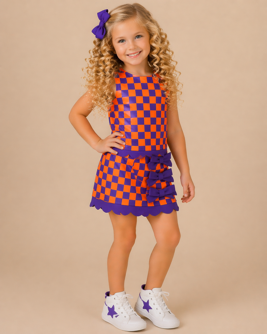 Young girl wearing a checkered dress with purple and orange pattern on a beige background