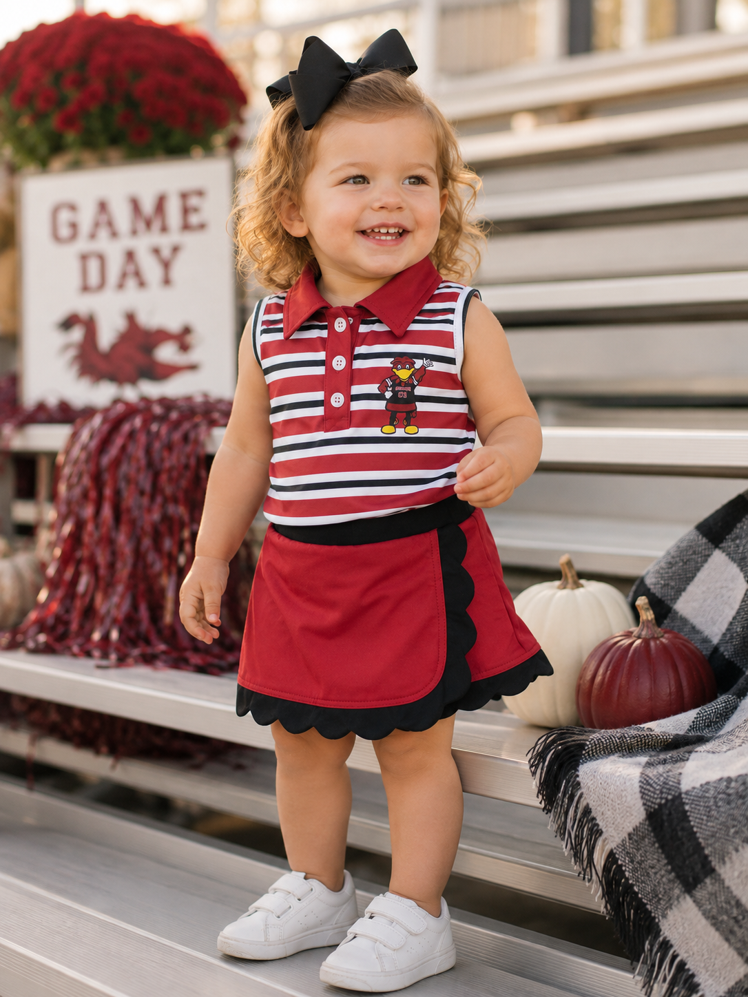 Toddler girl wearing garnet and black stripe mascot skort set on game day bleachers