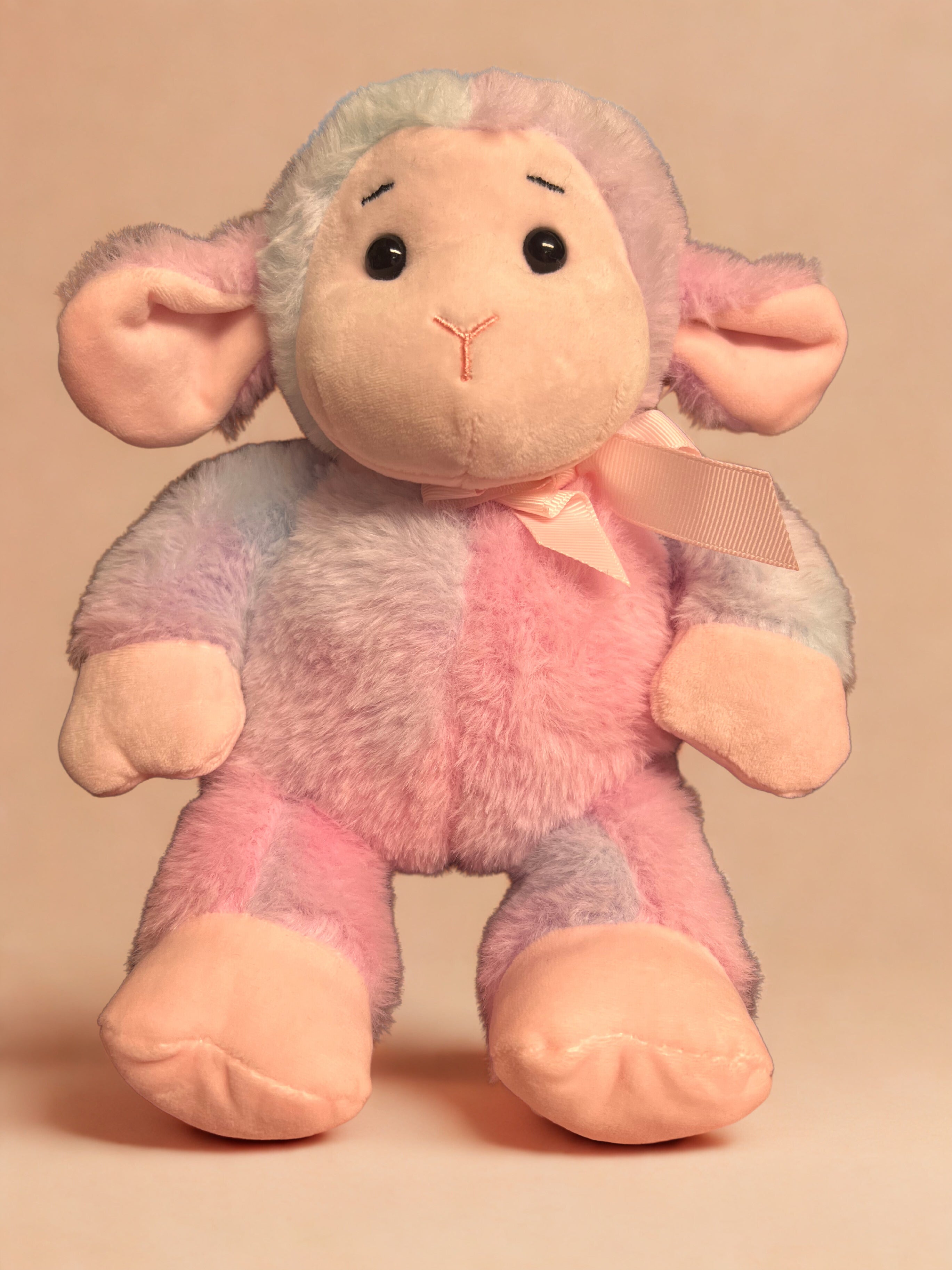 Plush toy sheep with pastel tie dye body on a beige background