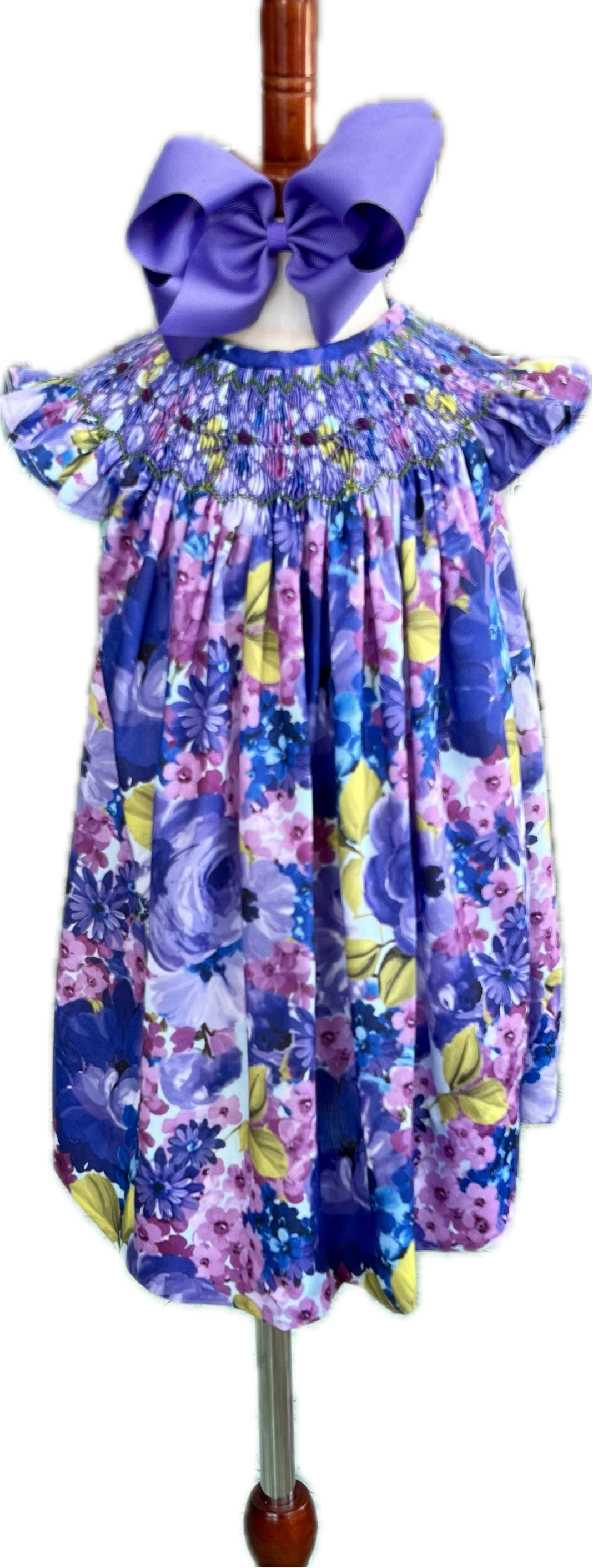 Floral dress with a large purple bow on a mannequin against a white background