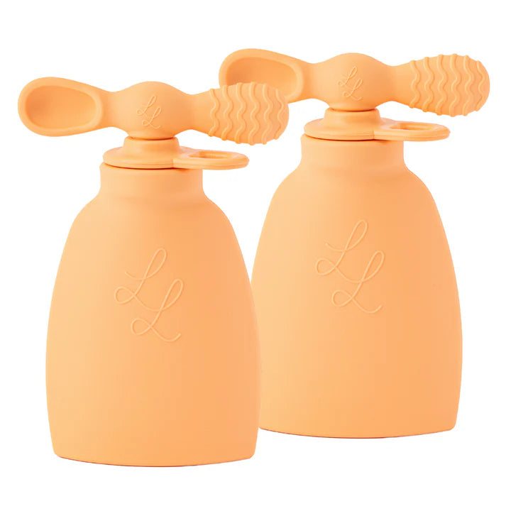Two peach-colored silicone bottles with sippy cup lids on a white background