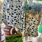 Children's clothing with sports-themed design on hangers in a store setting.