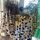 Children's patterned dresses hanging on a rack with wooden hangers.
