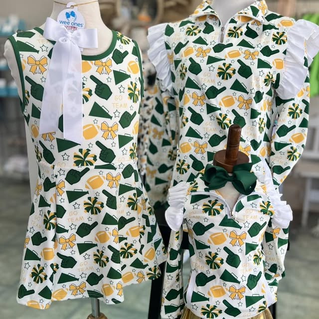Two children's outfits on mannequins with green, yellow, and white patterns.