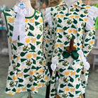 Two children's outfits on mannequins with green, yellow, and white patterns.