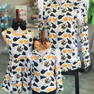 Children's clothing set with dresses and a jacket on mannequins against a blurred store background.