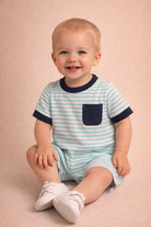 Child wearing a blue and white striped outfit with a pocket on a beige background