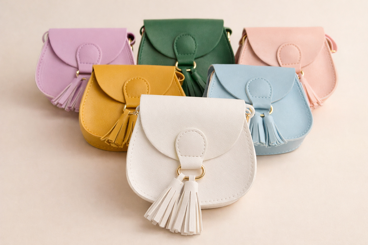 Set of colorful mini handbags with tassels on a beige background