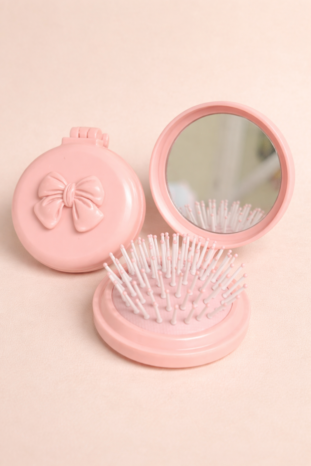 Pink cosmetic case with mirror and brush on a light pink background