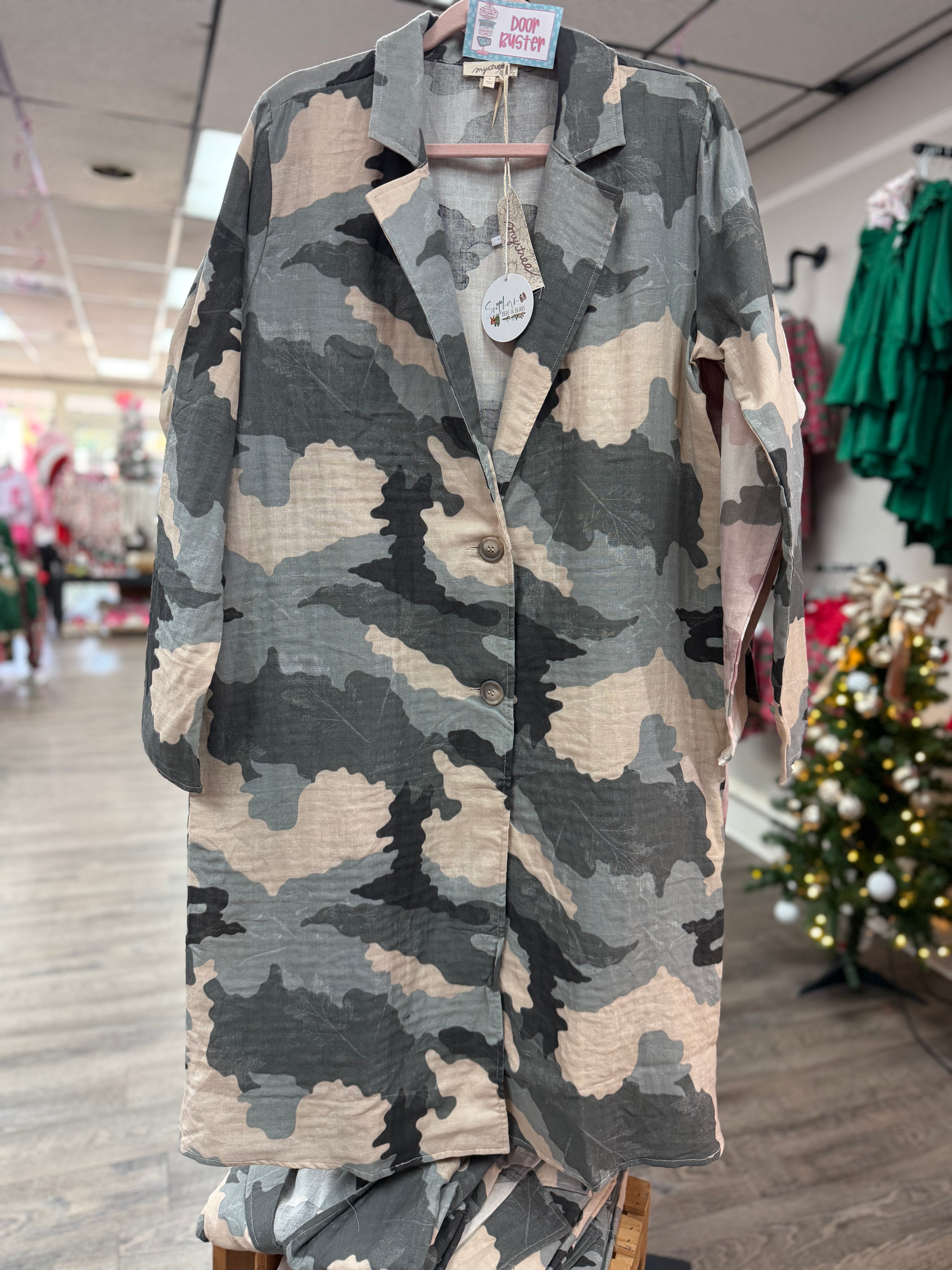 Camouflage shirt on a hanger in a store setting with Christmas decorations.