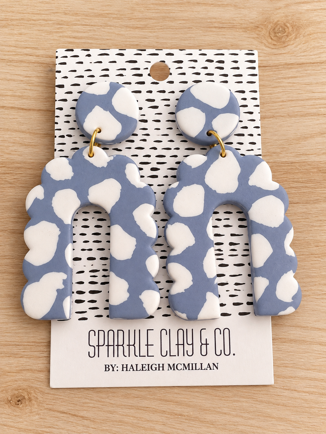 Blue-gray and white spotted clay earrings with round tops, scalloped arch drops, and gold-tone connecting rings