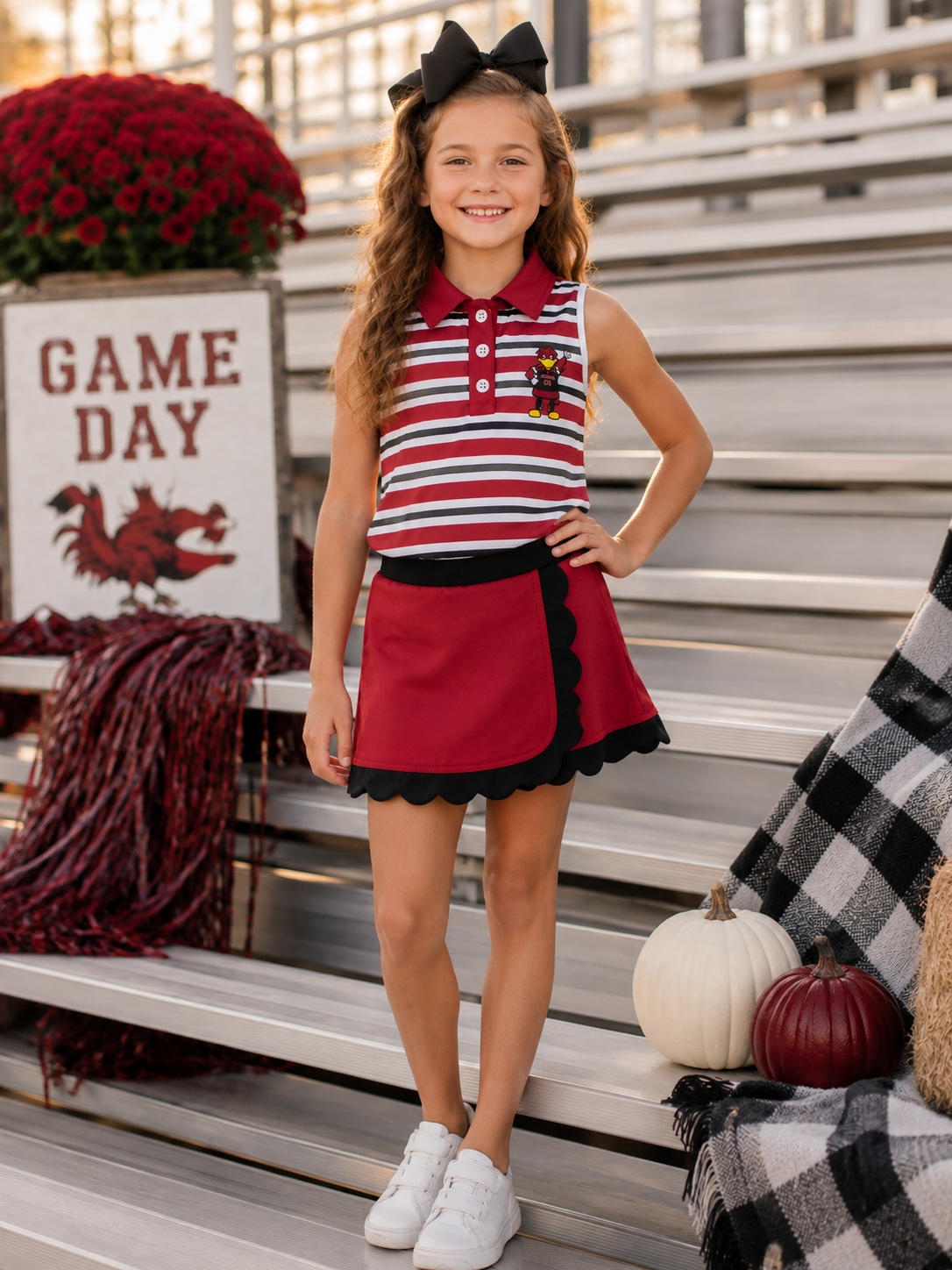 Girl wearing garnet and black stripe mascot skort set on game day bleachers