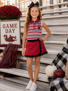 Girl wearing garnet and black stripe mascot skort set on game day bleachers