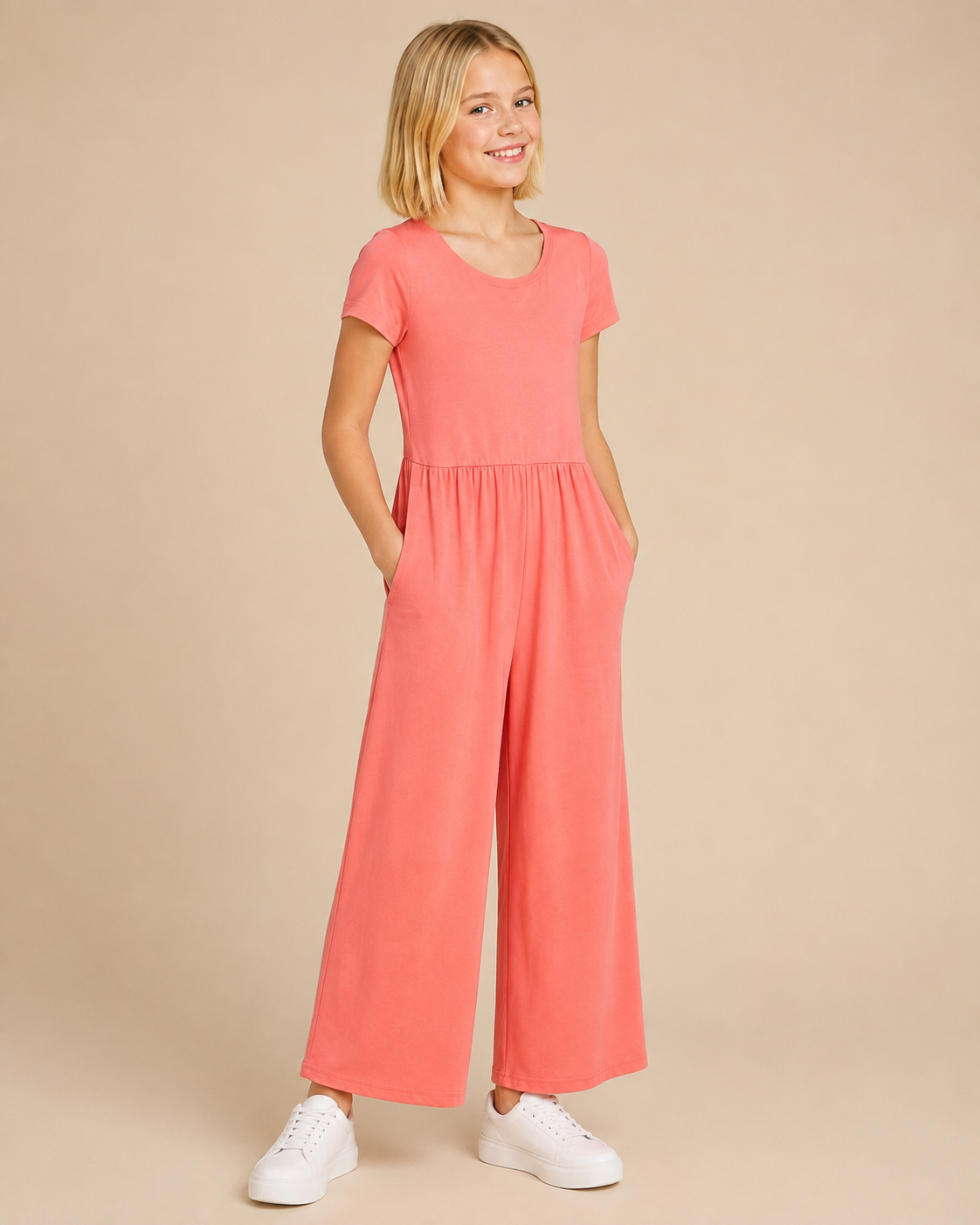 Tween model wearing a rosebud colored jumper on a beige background.