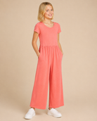 Tween model wearing a rosebud colored jumper on a beige background.