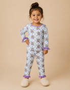 Toddler girl wearing a astronaut print lounge set on beige background with slippers.