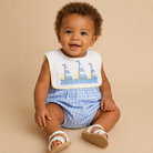 Baby boy wearing a blue gingham bubble with sailboat embroidery.