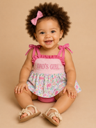 Baby girl wearing a pink outfit with 'Dad's Girl' text on a beige background