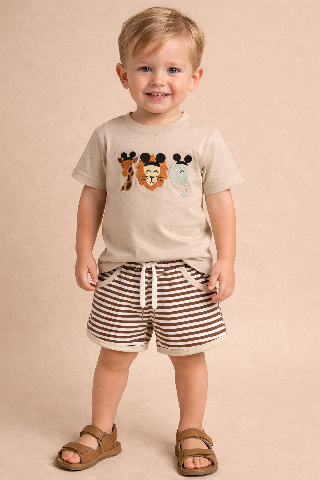 Child wearing a beige t-shirt with animal prints and striped shorts on a beige background