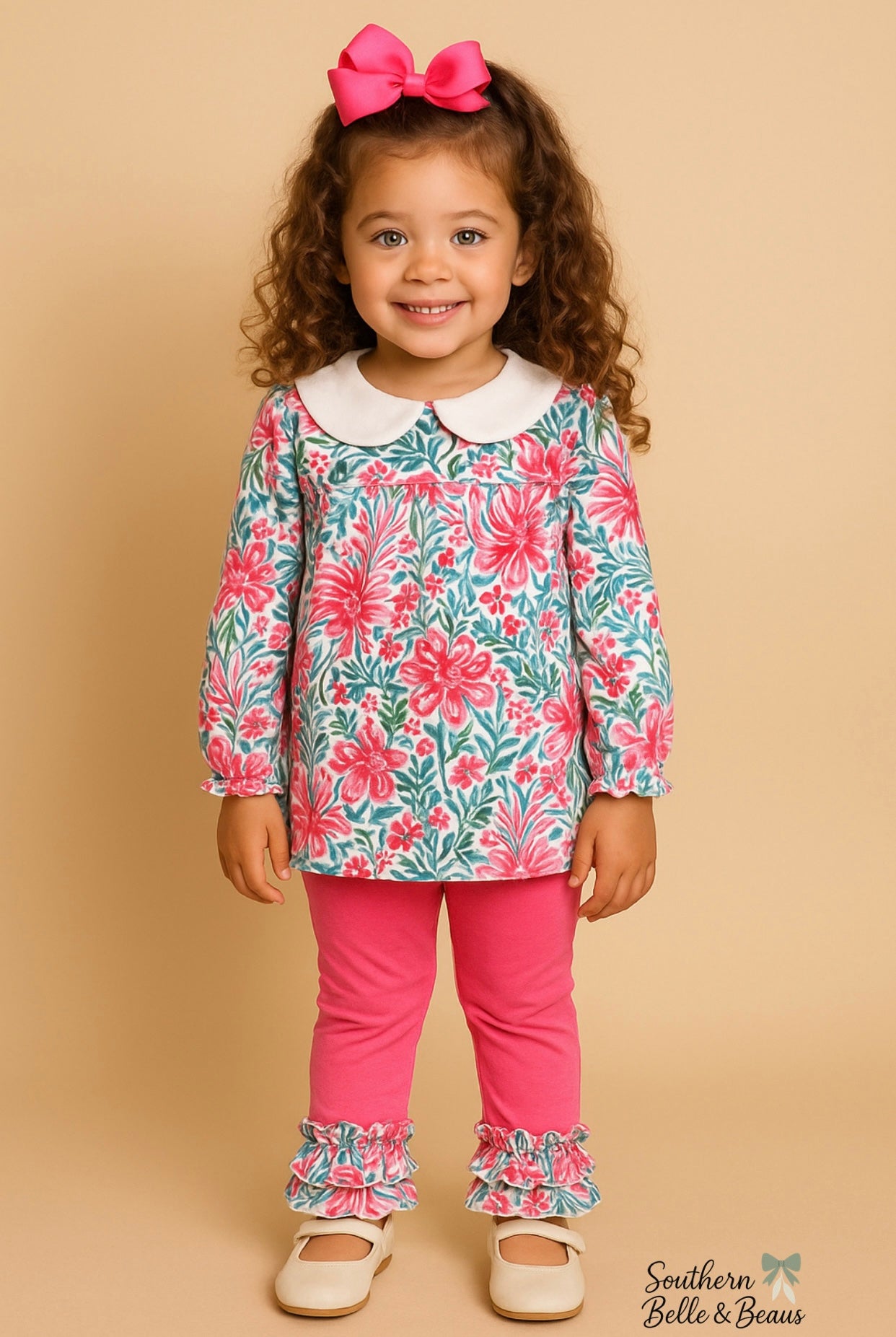 Young girl wearing a floral top and pink pants with a bow on a beige background