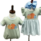 Two children's outfits on mannequins with pumpkin design on a light green background