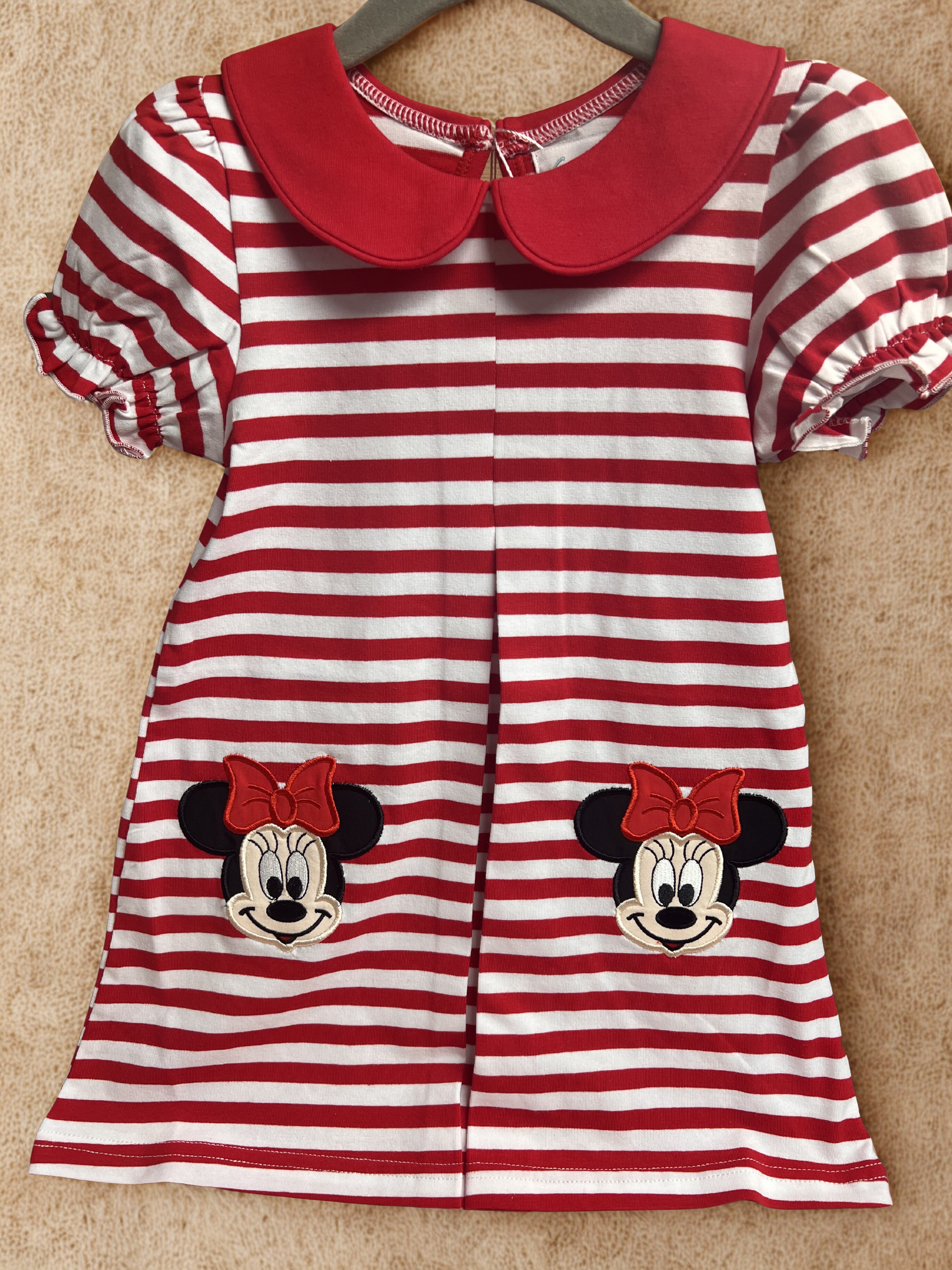 Red and white striped dress with faces on a beige surface