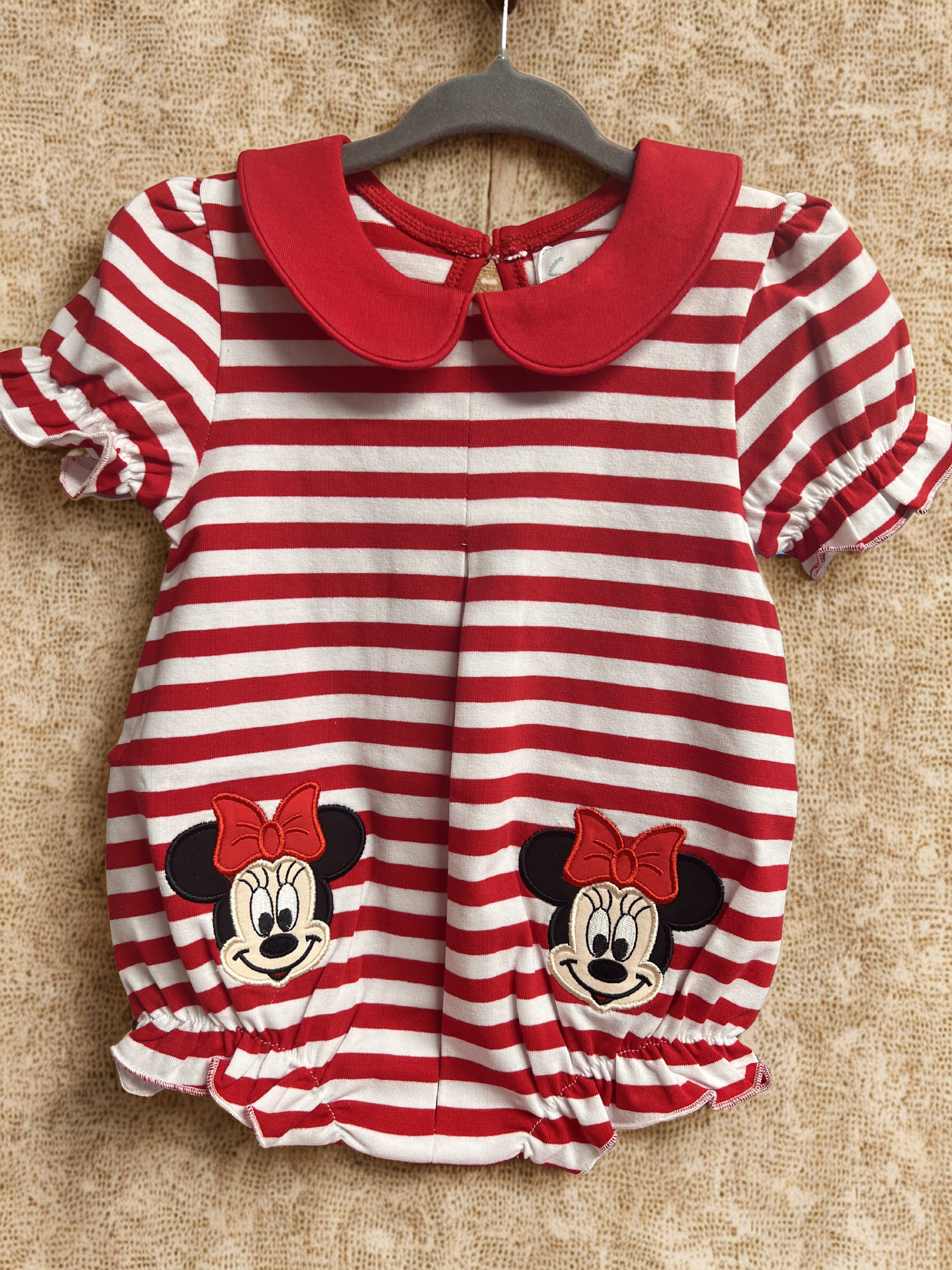 Red and white striped baby dress with faces on a textured surface