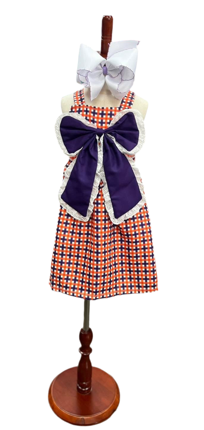 Plaid apron with a large purple bow on a wooden mannequin stand against a white background