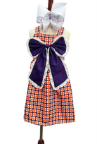Dress with large purple bow and checkered pattern on a mannequin against a white background