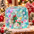 Christmas snow globe squishy cube with a snowman, Christmas tree, and snowflake confetti inside the gel