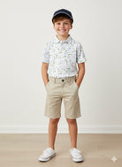 Boy wearing golf themed short sleeve polo with khaki shorts. 