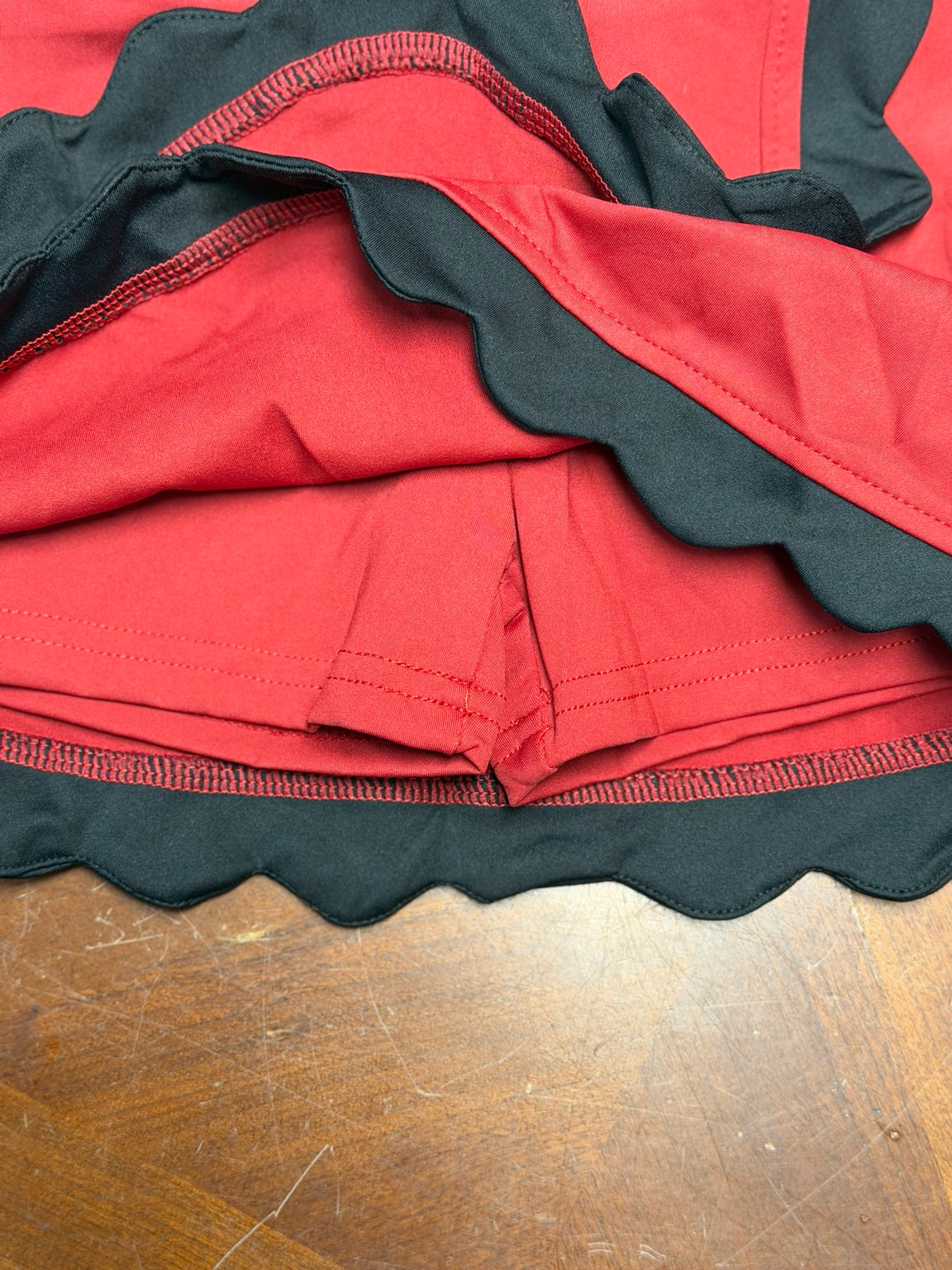 Close-up detail of garnet skort with black scallop trim and built-in shorts
