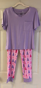 Lavender short-sleeve top with pocket paired with pink lounge pants featuring purple and magenta Christmas trees and bows.