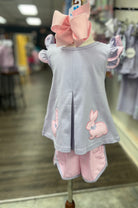 Children's outfit with a gray top and pink checkered pants on a mannequin in a store setting.