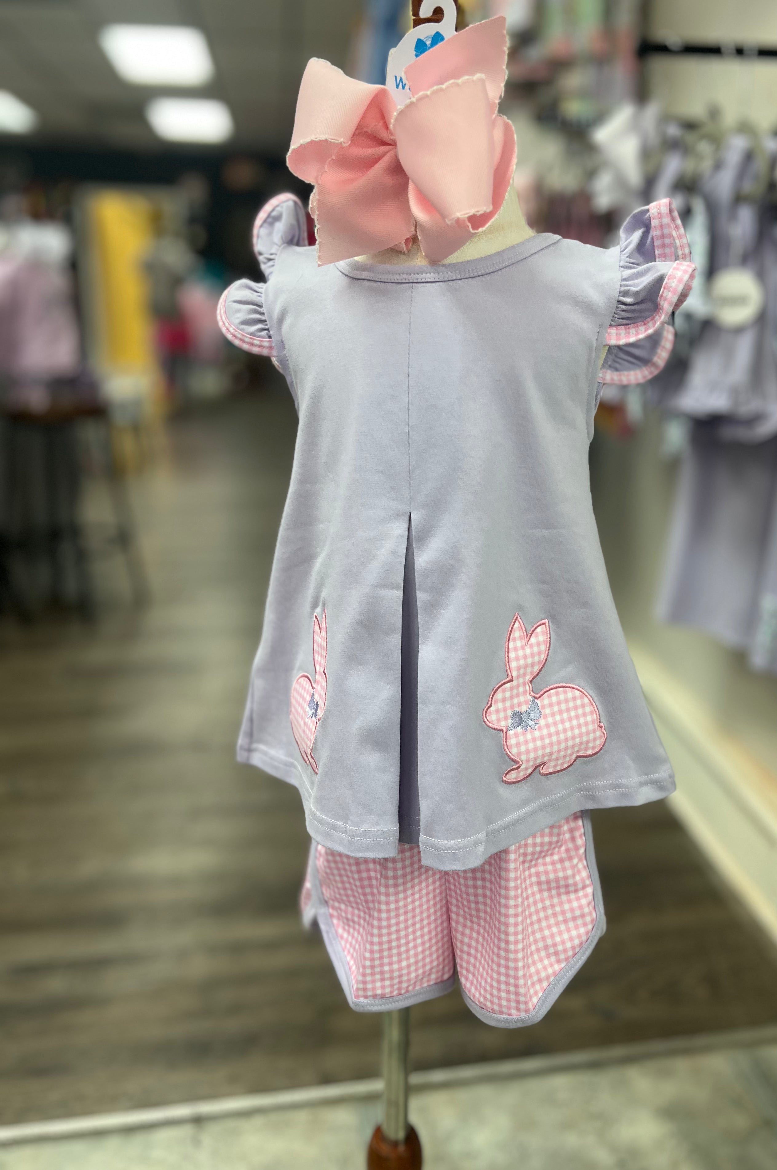 Children's outfit with a gray top and pink checkered pants on a mannequin in a store setting.