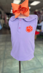Purple polo shirt with orange logo on a mannequin head with an orange bow.