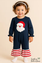 Child wearing a navy blue outfit with a Santa face design on a beige background