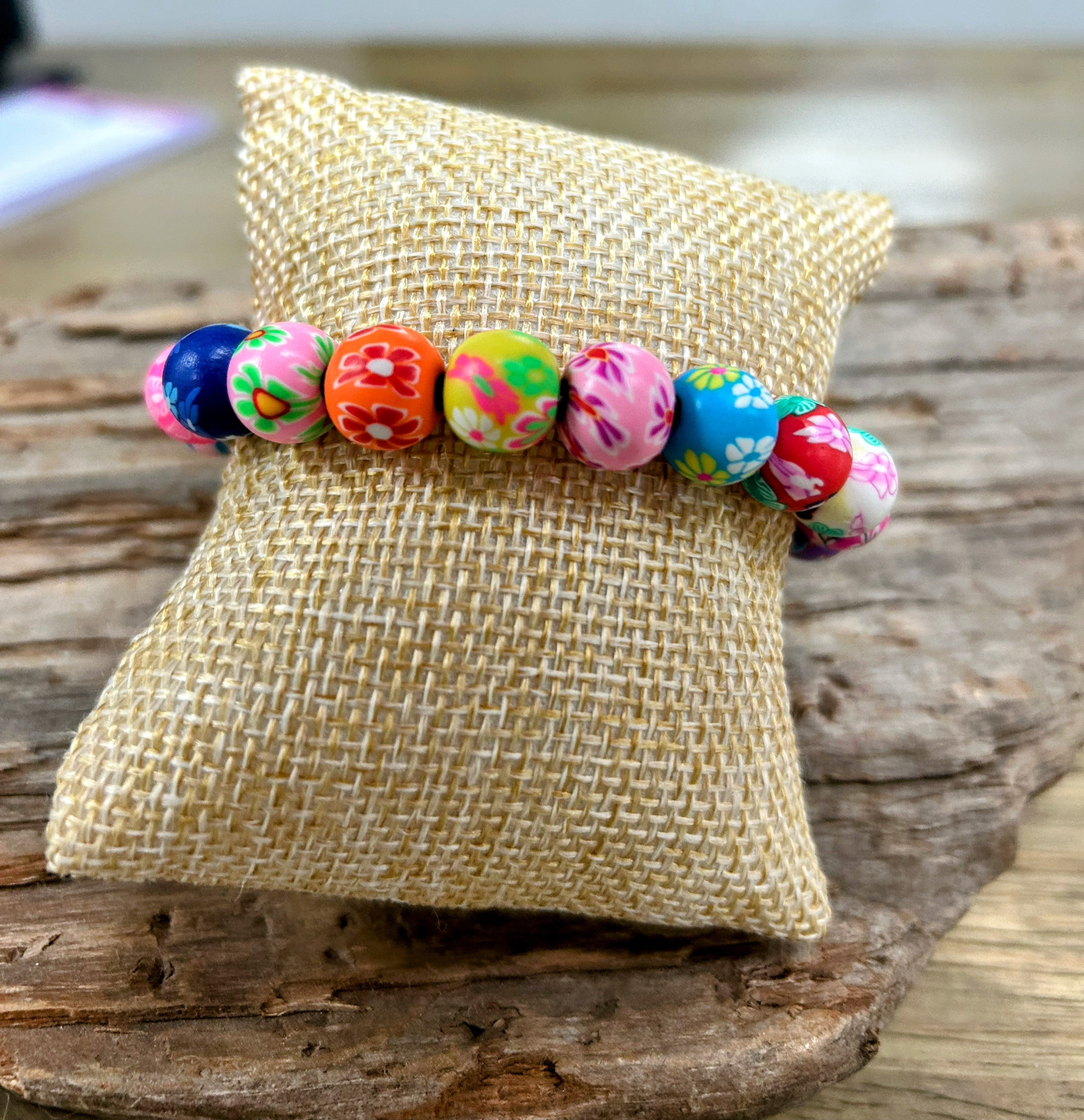 Colorful beaded bracelet on a textured pillow with a wooden background