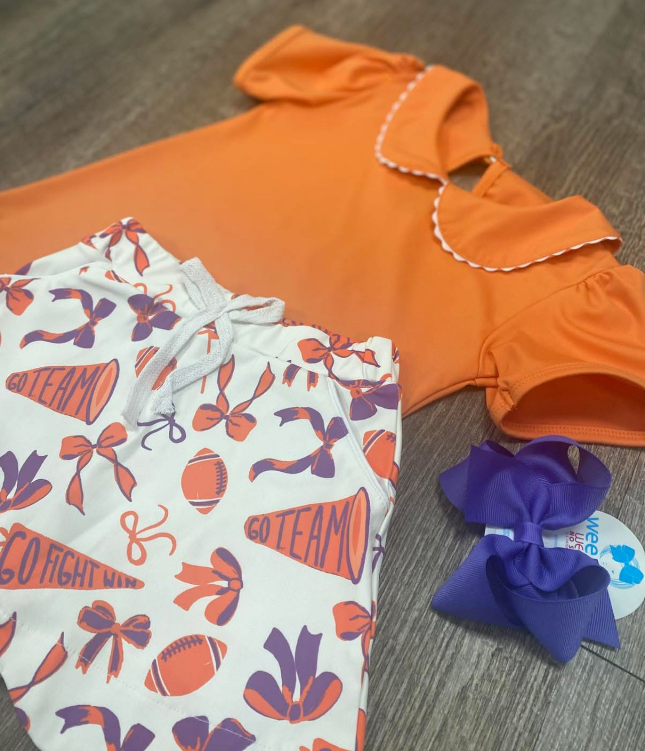 Orange athletic collared top with orange & purple skort that says "Go Team" "Go Fight Win"