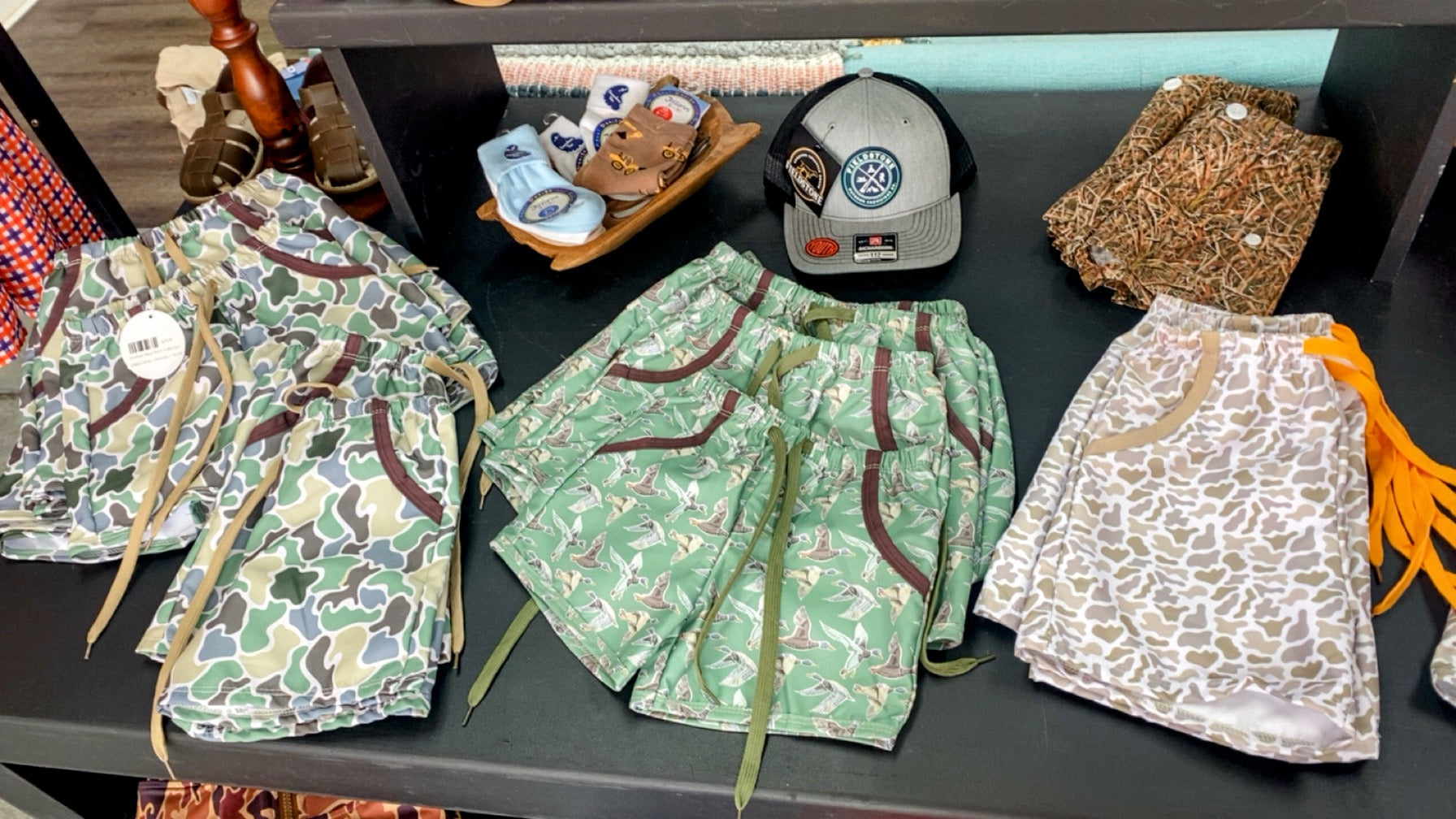 Collection of patterned bags on a table with a cap and other items in the background.