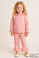 Young girl wearing a pink outfit with ruffled details.