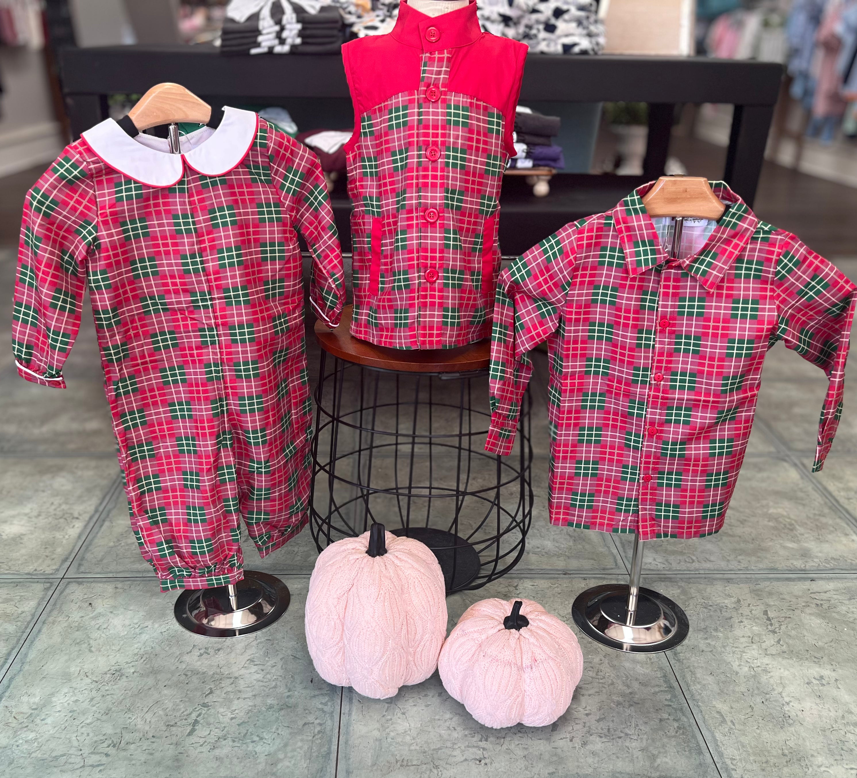 The set includes a red and green plaid bubble romper with a white Peter Pan collar, a matching plaid button-up boys’ shirt, and a sleeveless plaid vest with a solid red yoke and buttons. 